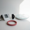 Blood pressure monitor, smartwatch, and scale on a white surface