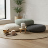 Stack of round cushions on a wooden floor with a diffuser and small items.